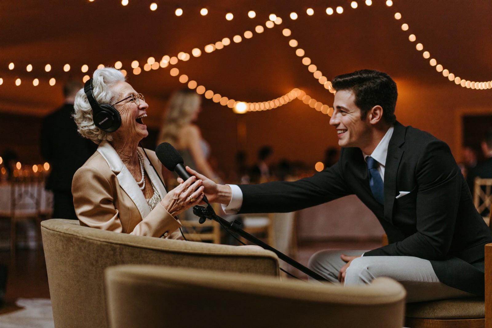 A grandmother in headphones laughing into the microphone while the Parea host guides the conversation